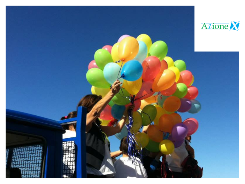 Questa immagine mostra bambini e psicologhe del Centro di ascolto mobile di Azione X OdV a Trapani che tengono in mano palloncini colorati