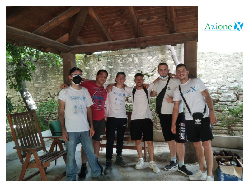 Questa immagine mostra i volontari di Azione X durante una pausa del ripristino del giardino del Serraino Vulpitta di Trapani