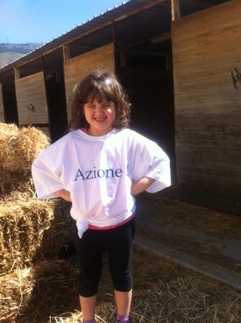 Il contesto del progetto La fattoria sociale di Azione X Organizzazione di volontariato di Trapani e bambina con maglietta di Azione X